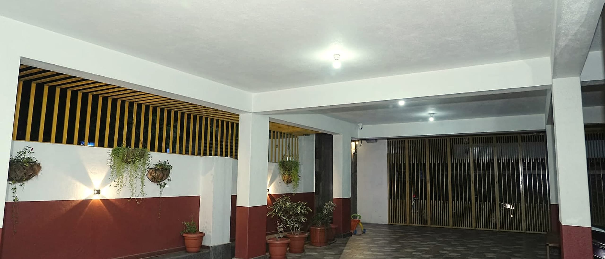 The covered ground floor at night, lit warmly, with plants along a timber screen.
